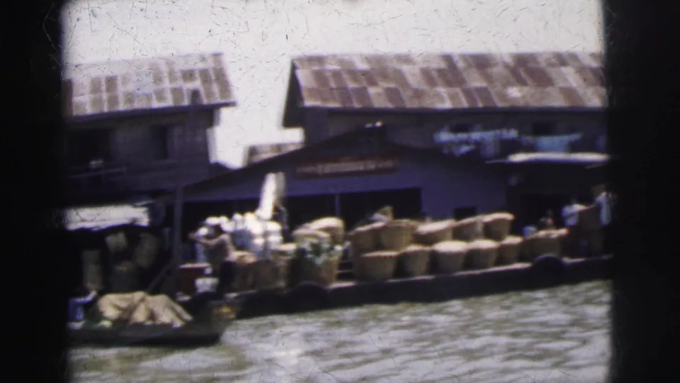 1962 Calcutta river market view with loaded boats, woven baskets, dockside figures, and low wooden buildings along the water.
