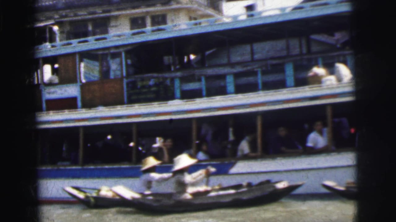 1962 Calcutta river scene with a multi-deck passenger vessel and a small wooden boat carrying paddlers in conical hats.