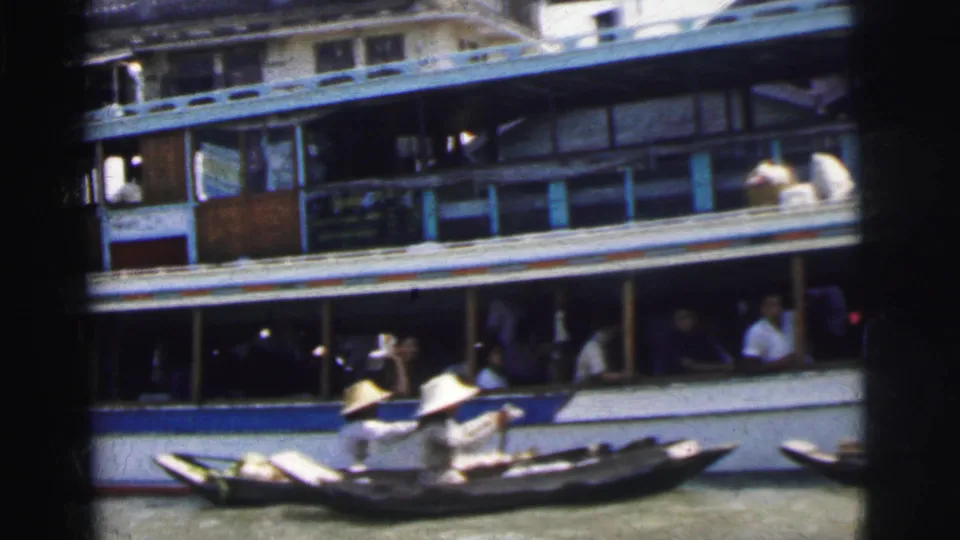 1962 Calcutta river scene with a multi-deck passenger vessel and a small wooden boat carrying paddlers in conical hats.