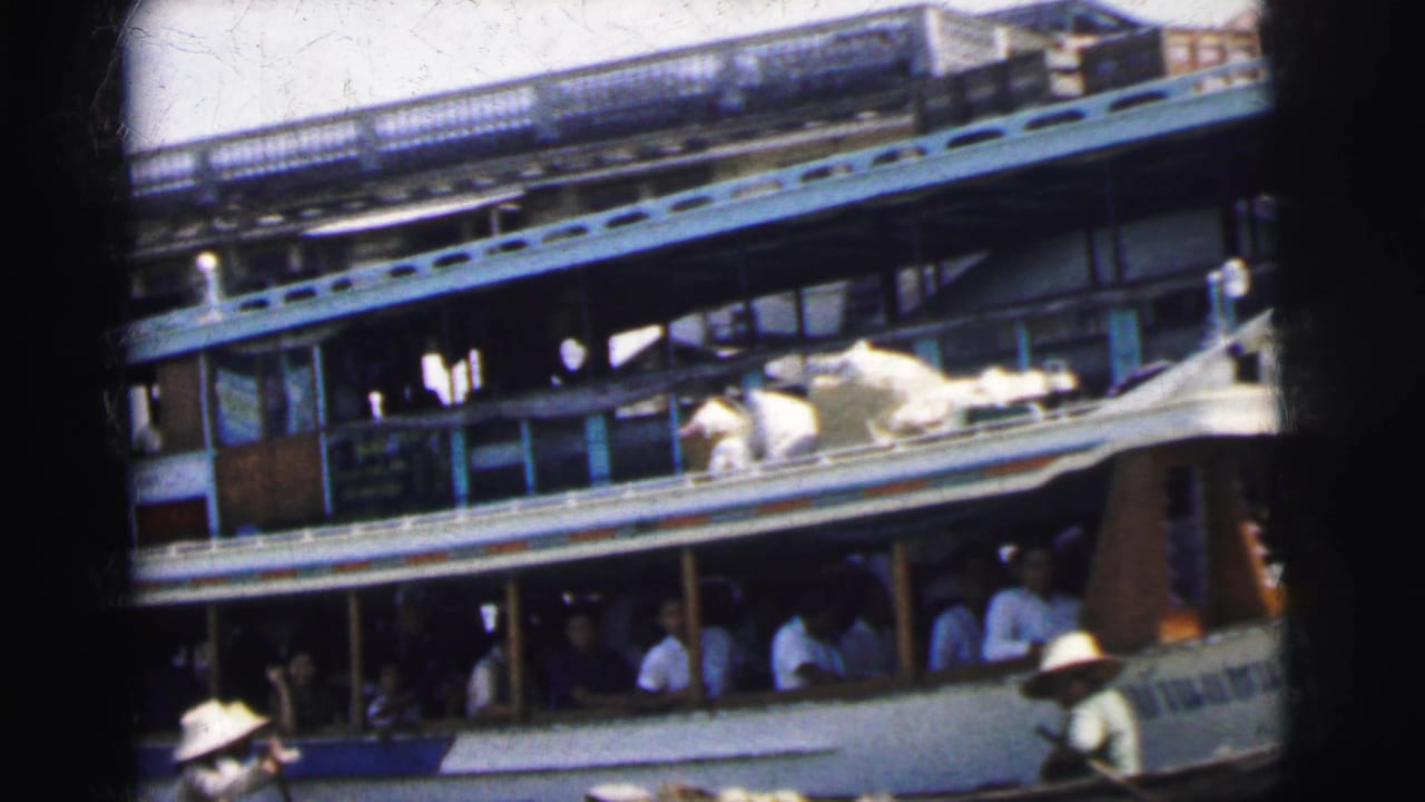 A large river passenger vessel in Calcutta, India, with seated passengers and small boats crossing near its side.