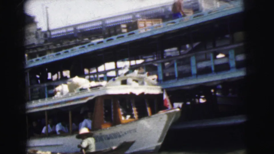 Close view of the bow area of a multi-deck passenger boat with a small paddled boat passing in the foreground.
