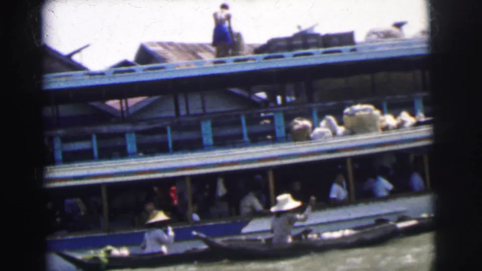 A crowded boat in 1962 Calcutta shows passengers under the deck while a smaller boat sits beside the hull.