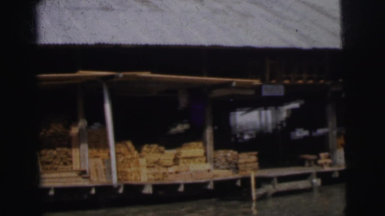 Wooden riverside shop with stacked goods under a corrugated roof.