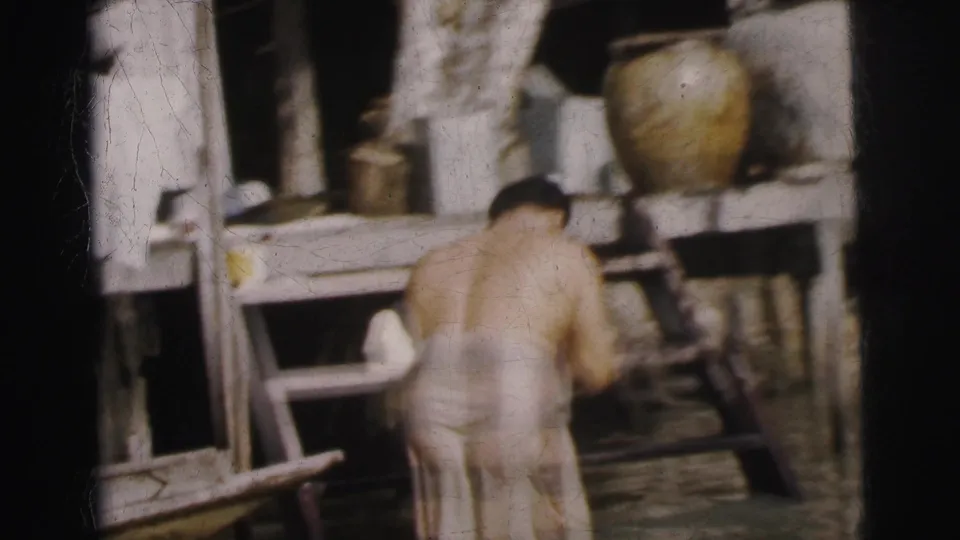 1962 Calcutta frame showing an adult near stairs and a raised wooden dwelling, with floodwater at the lower level.