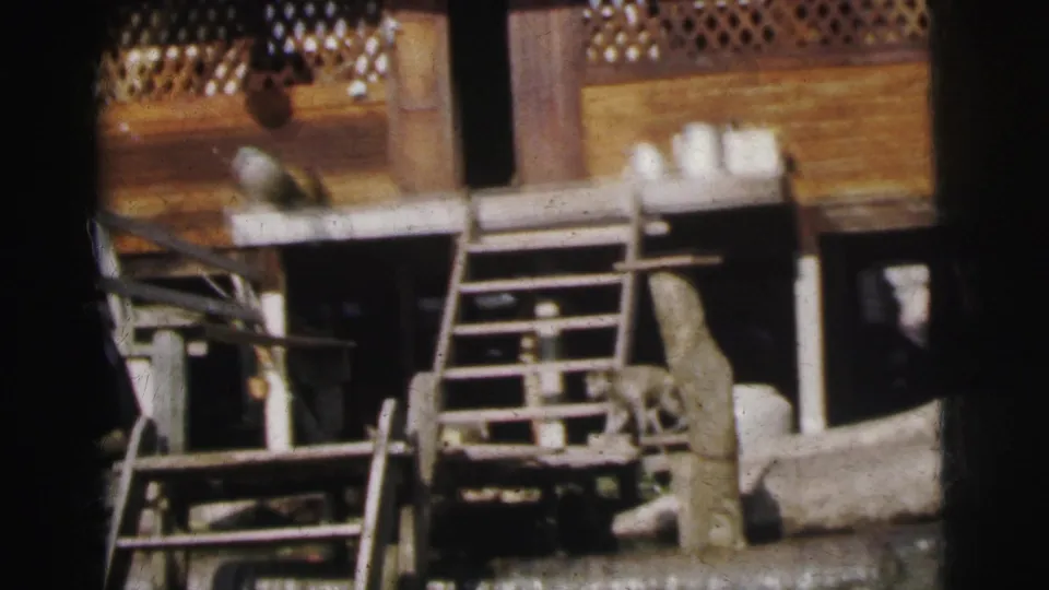 1962 Calcutta frame showing a wooden riverside building edge with steps, railing detail, posts, and objects beside the water.