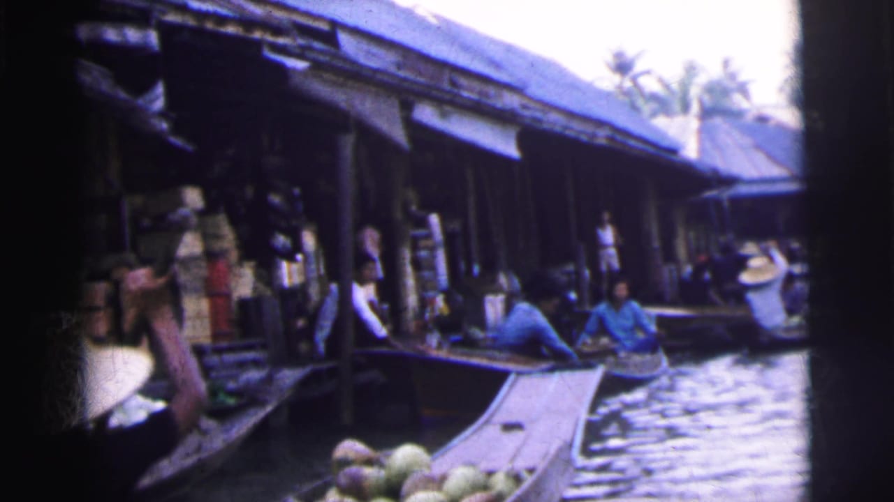 1962 Calcutta home-movie frame showing small boats with fruit near waterside market buildings and visible vendors.