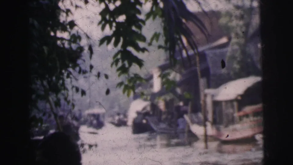 Leafy 1962 Calcutta river view with canoes or small boats moving near waterside structures.