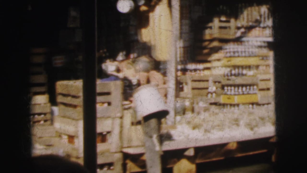 1962 Calcutta market view with stacked crates, rows of bottles, and ceramic vessels in soft 8mm color.