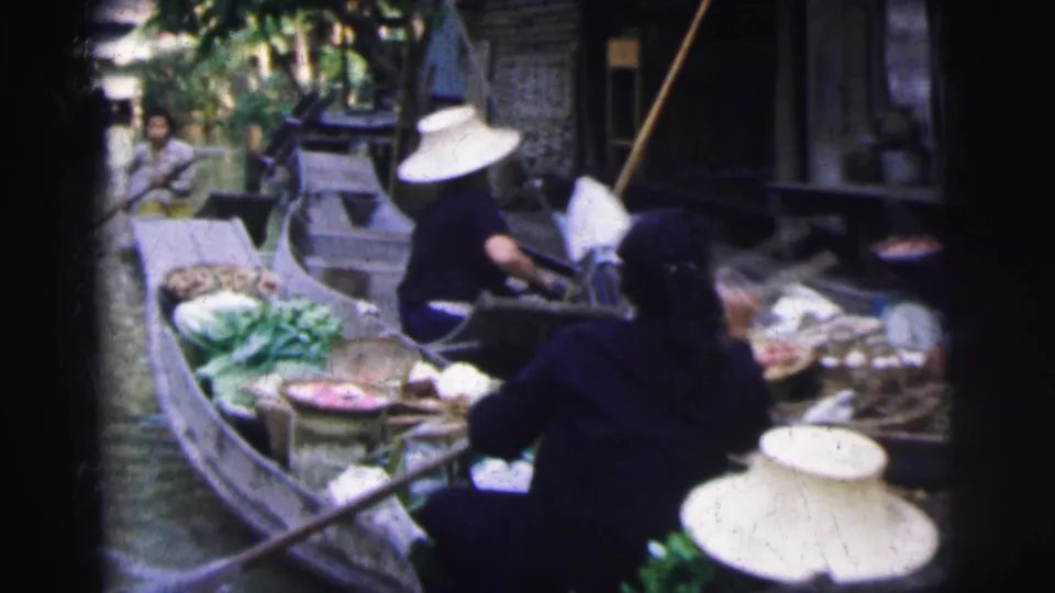 1962 Calcutta market scene with produce-filled boats, vendors, woven hats, and canal-side dwellings in soft 8mm color.