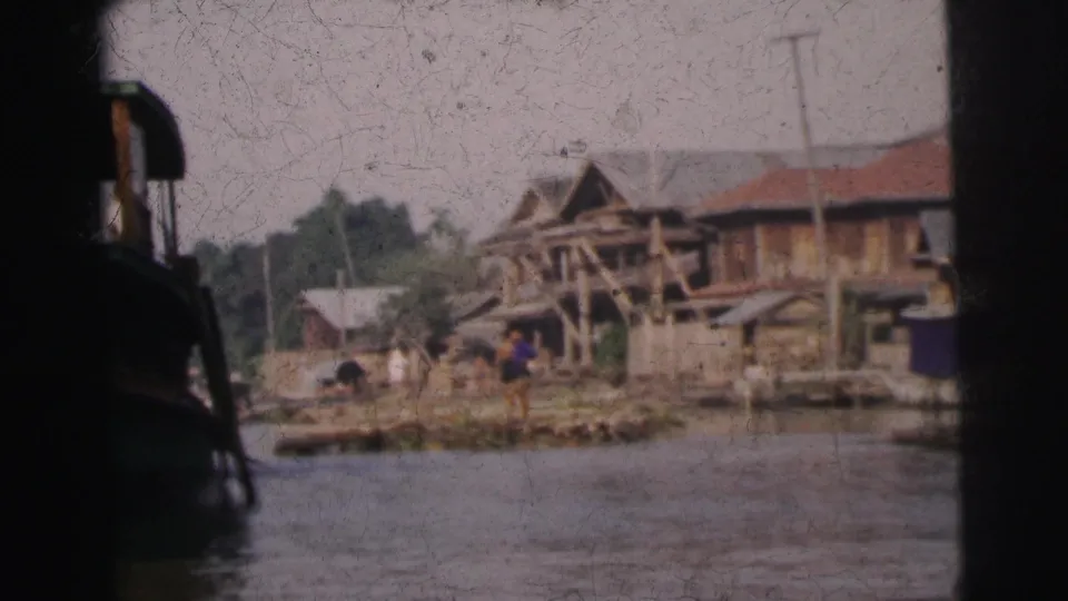 1962 Calcutta shoreline with wooden huts, a small figure near the water, and river surface in the foreground.