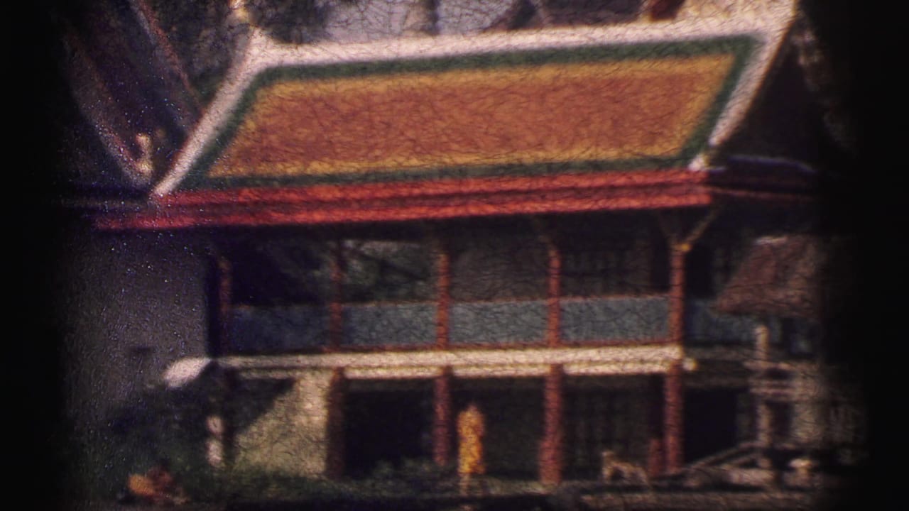 Ornate building facade with a colorful roof and a monk near the entrance.
