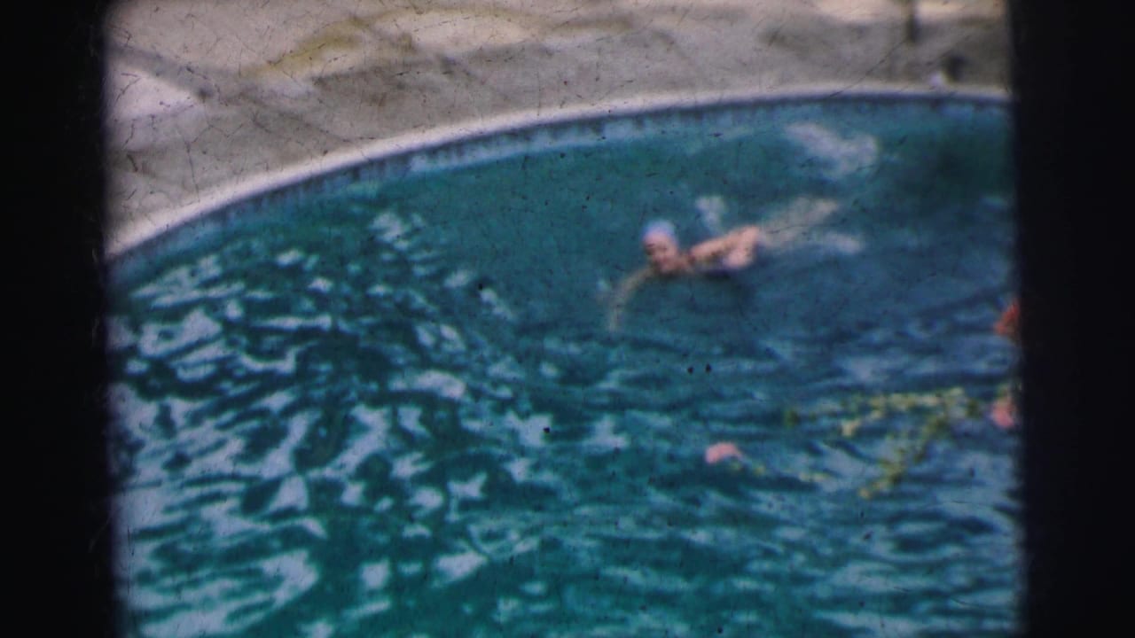 The woman continues a crawl stroke in the Calcutta pool, partly blurred by motion and soft 8mm focus.