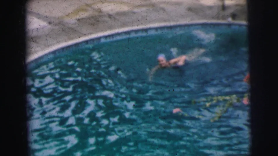 The woman continues a crawl stroke in the Calcutta pool, partly blurred by motion and soft 8mm focus.