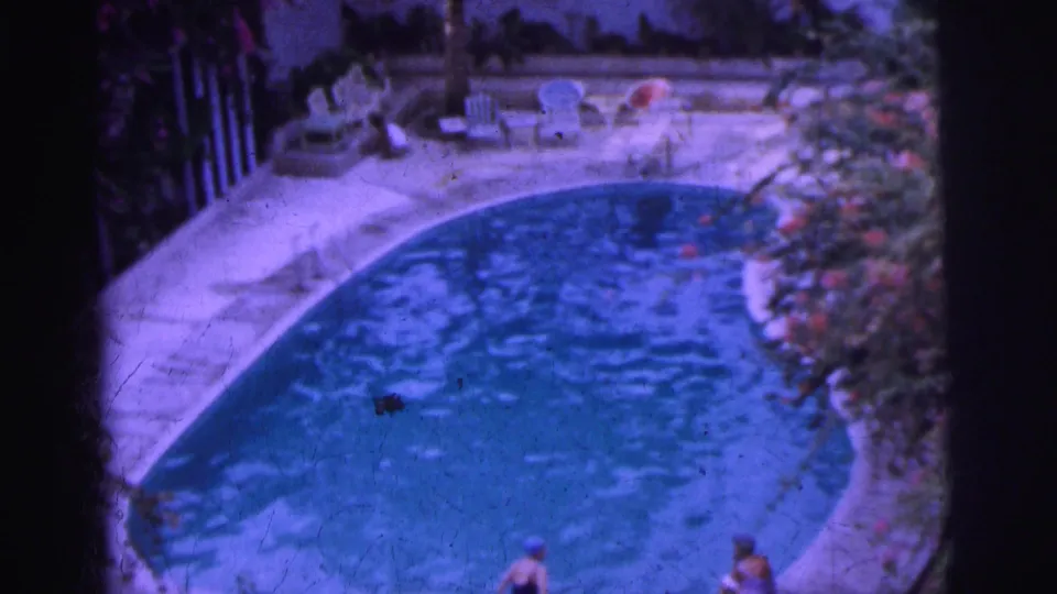 Soft 8mm frame from Calcutta in 1962 showing the pool curve, lounge seating, foliage and people at the lower edge.