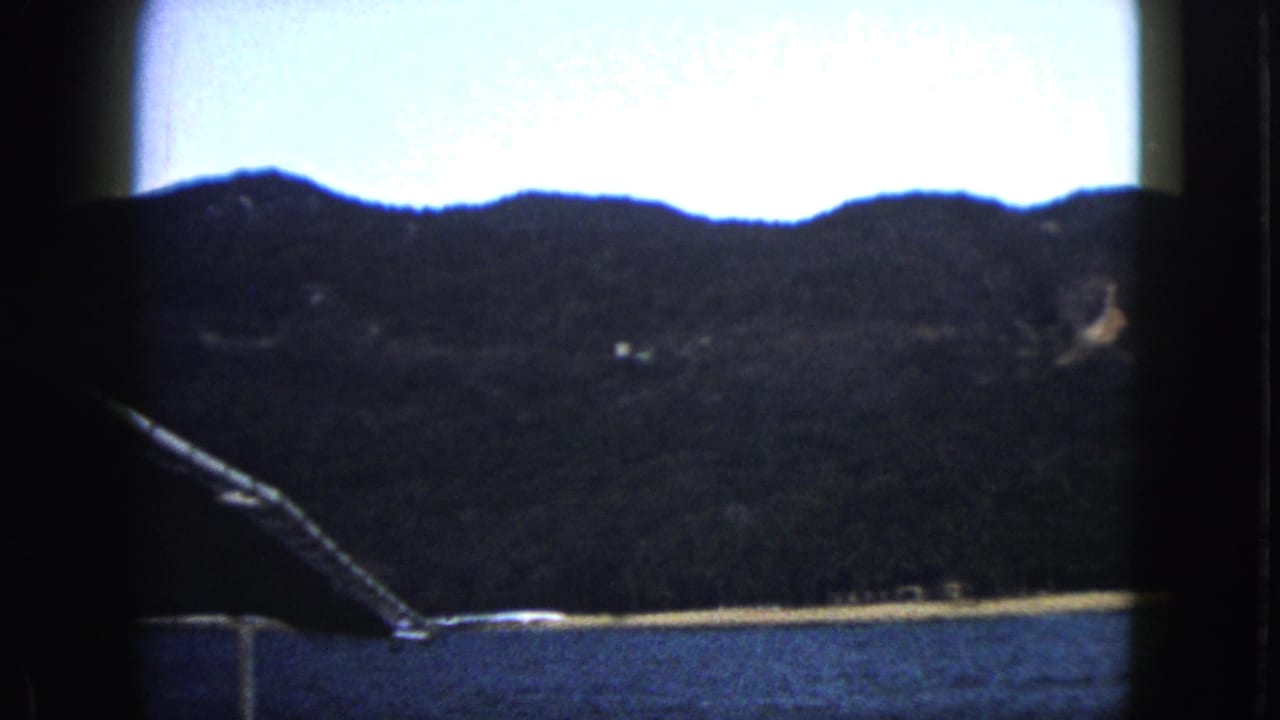 Dark coastal hills seen across water from a boat.