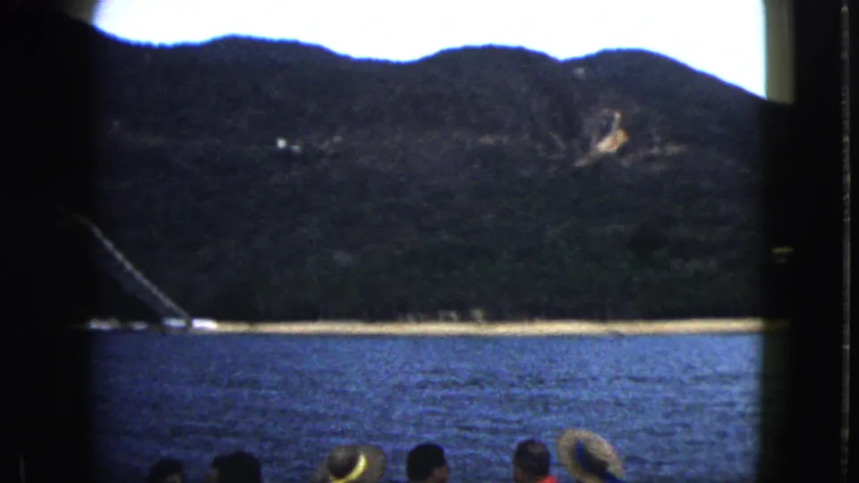 1962 coastal travel footage with passengers at the lower edge and Acapulco shoreline and mountains filling the view.