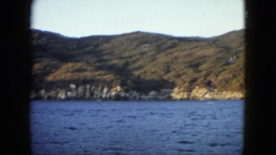 Acapulco shoreline and blue bay water fill the 8mm frame after the boat has moved out of view.
