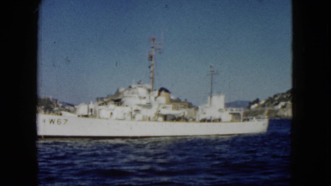 White vessel marked W67 on blue water with hills behind it.
