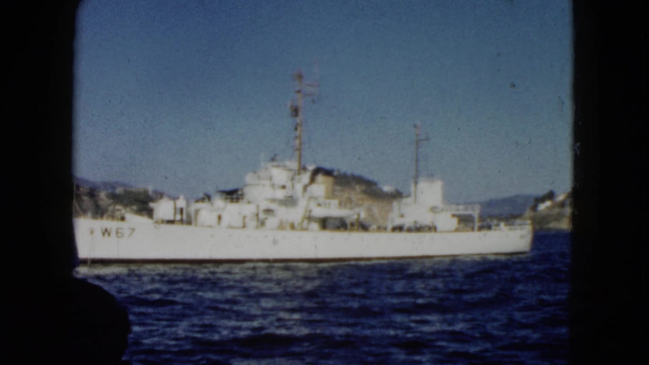 1962 Acapulco harbor view with the white W67-marked vessel centered against hills and shoreline structures.