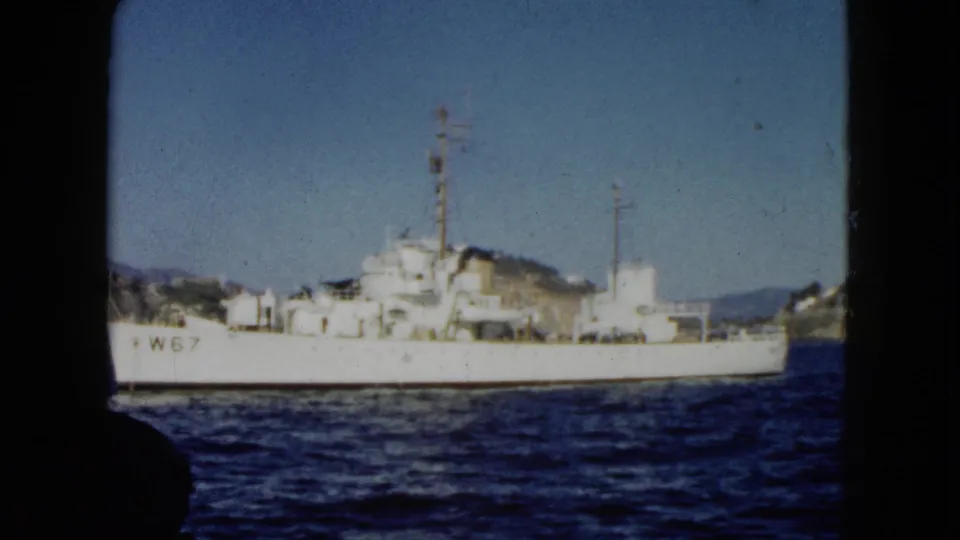 1962 Acapulco harbor view with the white W67-marked vessel centered against hills and shoreline structures.