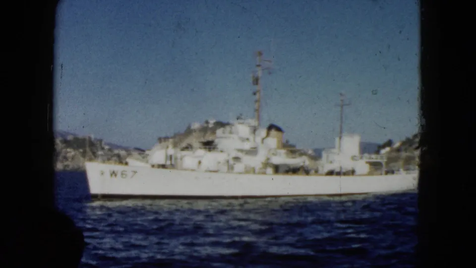 The W67-marked white vessel remains in view from the boat, with blue water, shoreline cliffs, and dark film or boat borders around the frame.