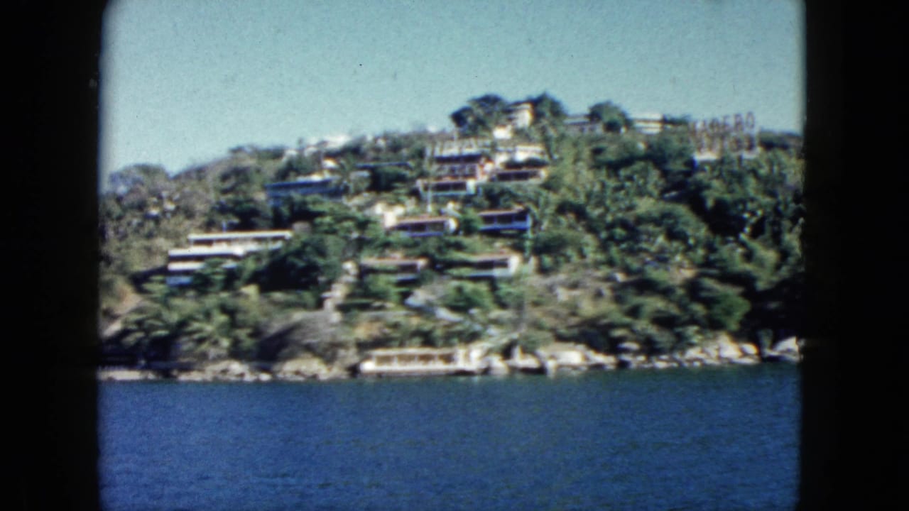 Hillside buildings and trees above a broad band of blue water.