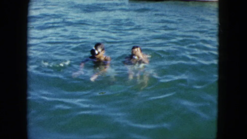 Two children swimming together in open water, Acapulco, Mexico, circa 1962, 8mm home-movie footage with characteristic period color.