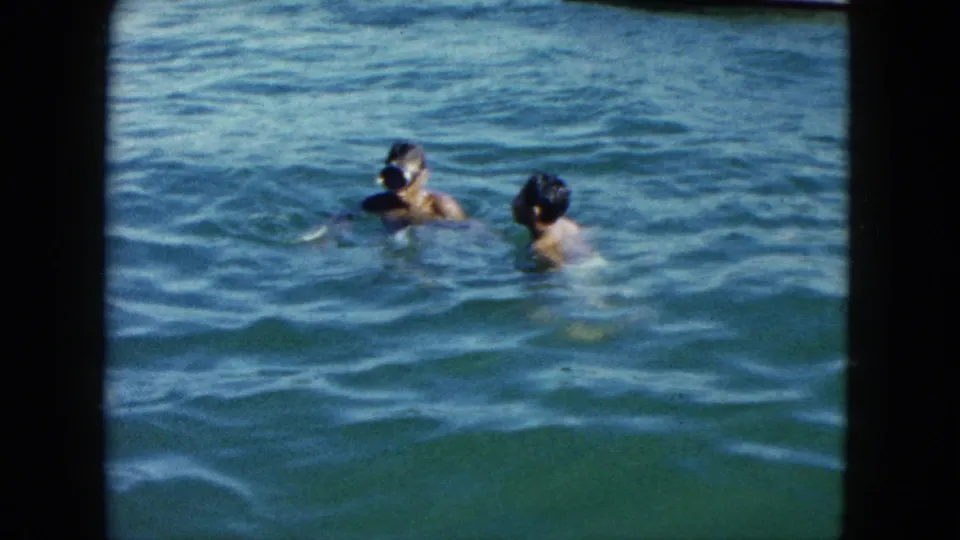 Two children swimming and playing in open water, Acapulco, Mexico, circa 1962; one appears to wear a snorkel mask; 8mm home-movie film.