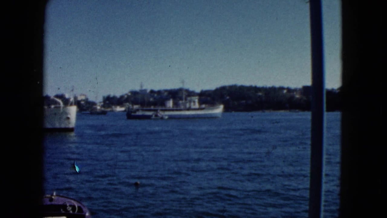 8mm home movie view from inside a boat showing a harbour bay circa 1962 Acapulco; large white cargo or passenger ship at left, green hills behind.