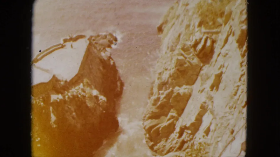 Close-up of rugged cliff terrain, likely in the Acapulco, Mexico area, circa 1962, showing amber dye shift and coarse grain characteristic of 8mm home movie film.