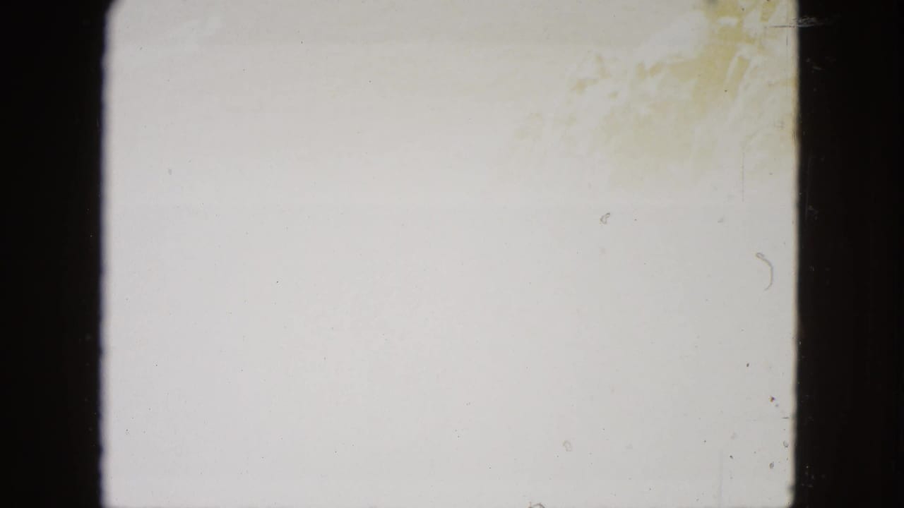 Overexposed blank frame from aged 8mm film reel, faint amber discoloration at upper right corner, consistent with film aging.