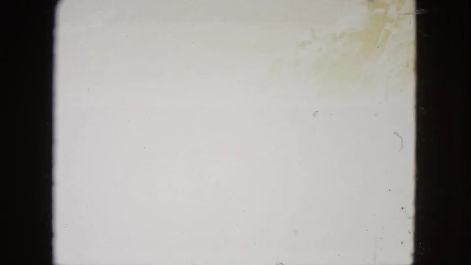Overexposed blank frame from aged 8mm film reel, faint amber discoloration at upper right corner, consistent with film aging.