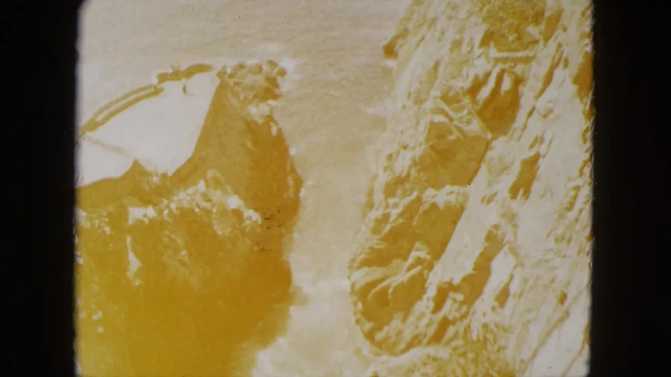 Final 8mm frame from Acapulco, 1962, showing advanced yellow-amber photochemical degradation; rocky cliff and curved railing are barely discernible through the dominant color cast