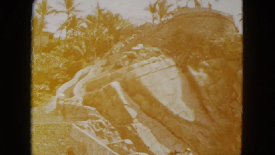 Late-reel 8mm frame with strong amber color shift over stone stairs and rocky hillside, Acapulco, c.1962 — characteristic film fade preceding blank leader.