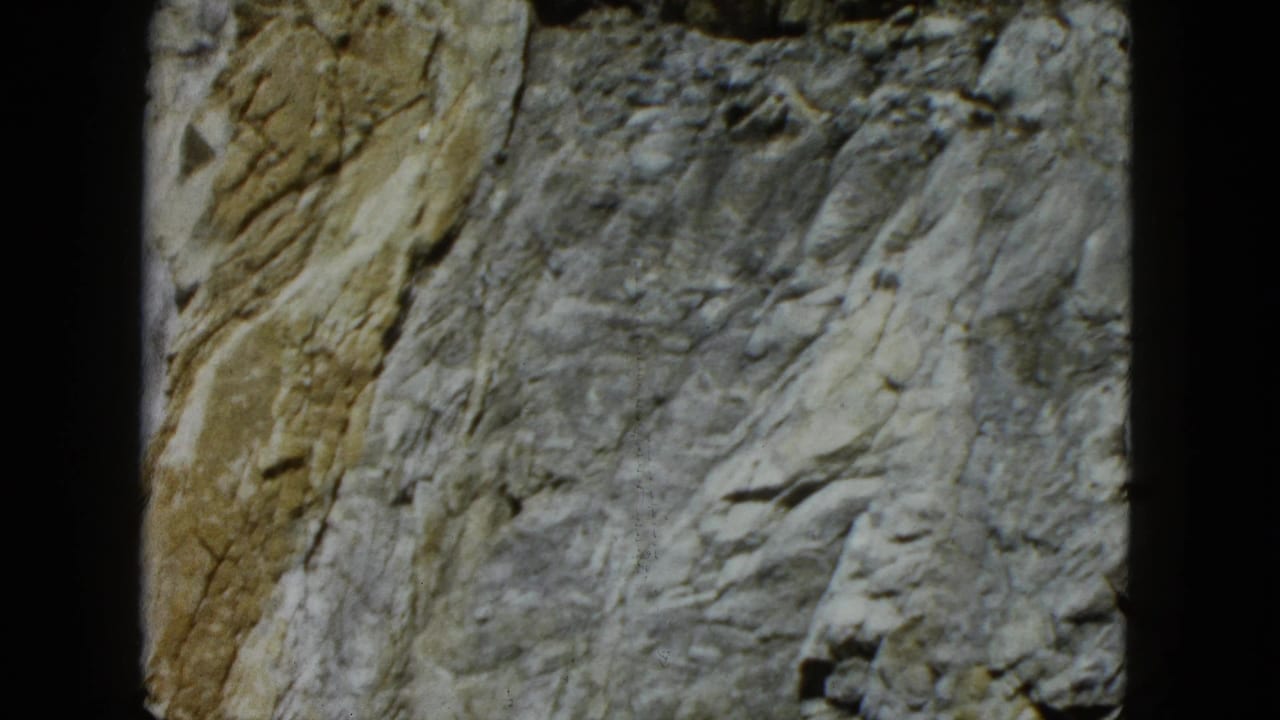 Steep gray and tan rock wall with rough crevices.