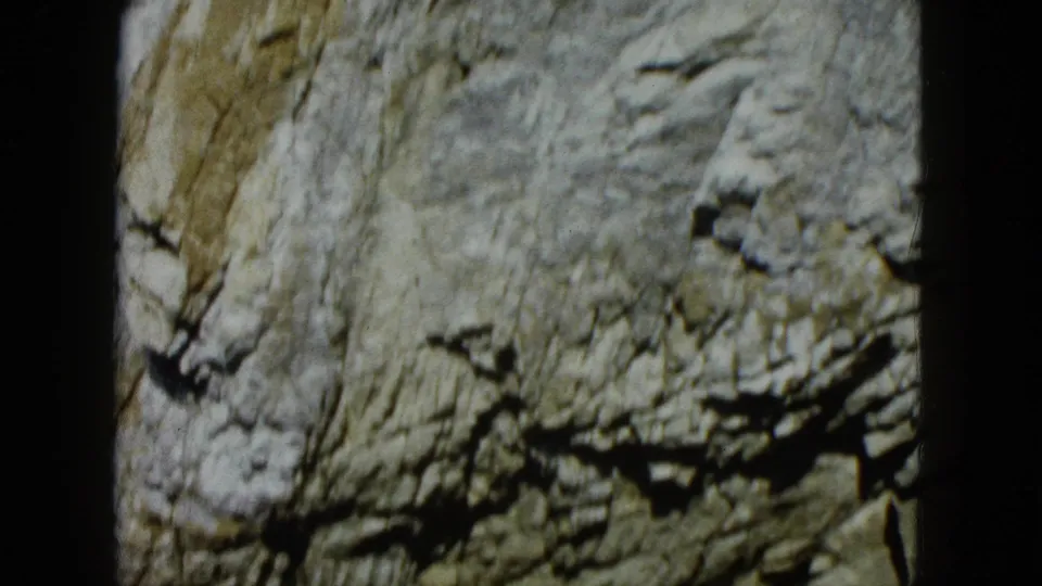 1962 Acapulco 8mm frame of a close rocky cliff surface, with darker ledges and soft focus from the film scan.