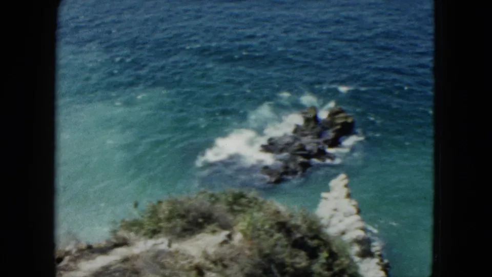 Rocky coastal outcroppings with breaking surf in deep blue sea, 8mm color footage reportedly from Acapulco, Mexico, 1962.