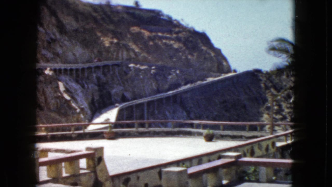 1960s 8mm frame showing resort terrace balustrade and cliffside concrete road in Acapulco, Mexico, circa 1962; warm saturated color typical of period reversal film.