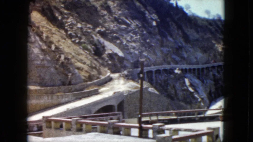 Pan shot revealing bare rocky mountain terrain above winding cliffside road and concrete balustrade, Acapulco, Mexico, circa 1962