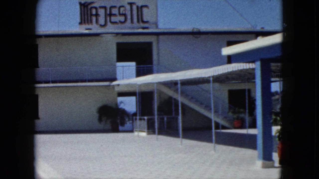 Hotel Majestic exterior with white facade, blue trim, covered walkway, stairs, and potted plants.