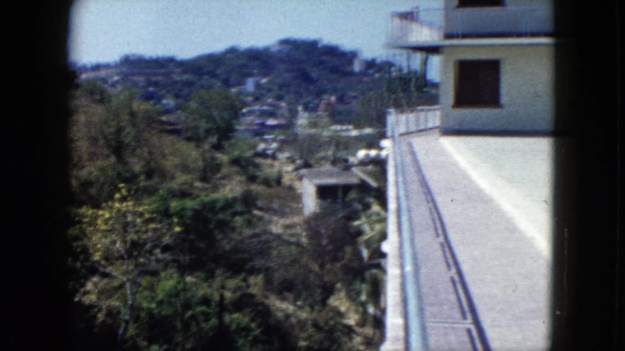 Hillside view beside a white building with balcony railings.