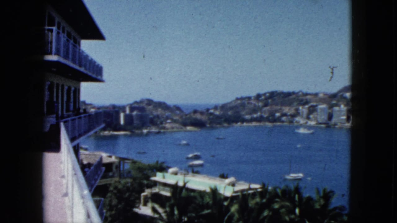 Balcony view over Acapulco Bay with boats, hillside buildings, and water below.
