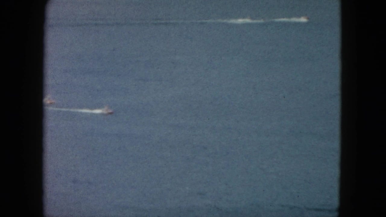 Small speedboat crossing blue ocean with a white wake trail.