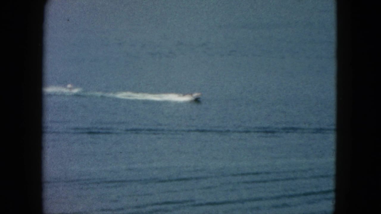 1962 Acapulco home-movie view of a small motorboat traveling across blue ocean water near the top of the frame.