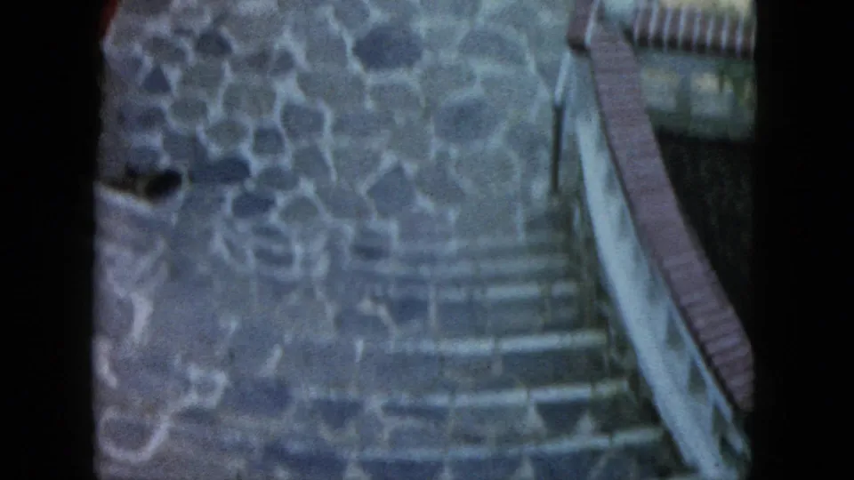1962 Acapulco home-movie frame with stone steps, irregular paving, a low wall, and muted film color.