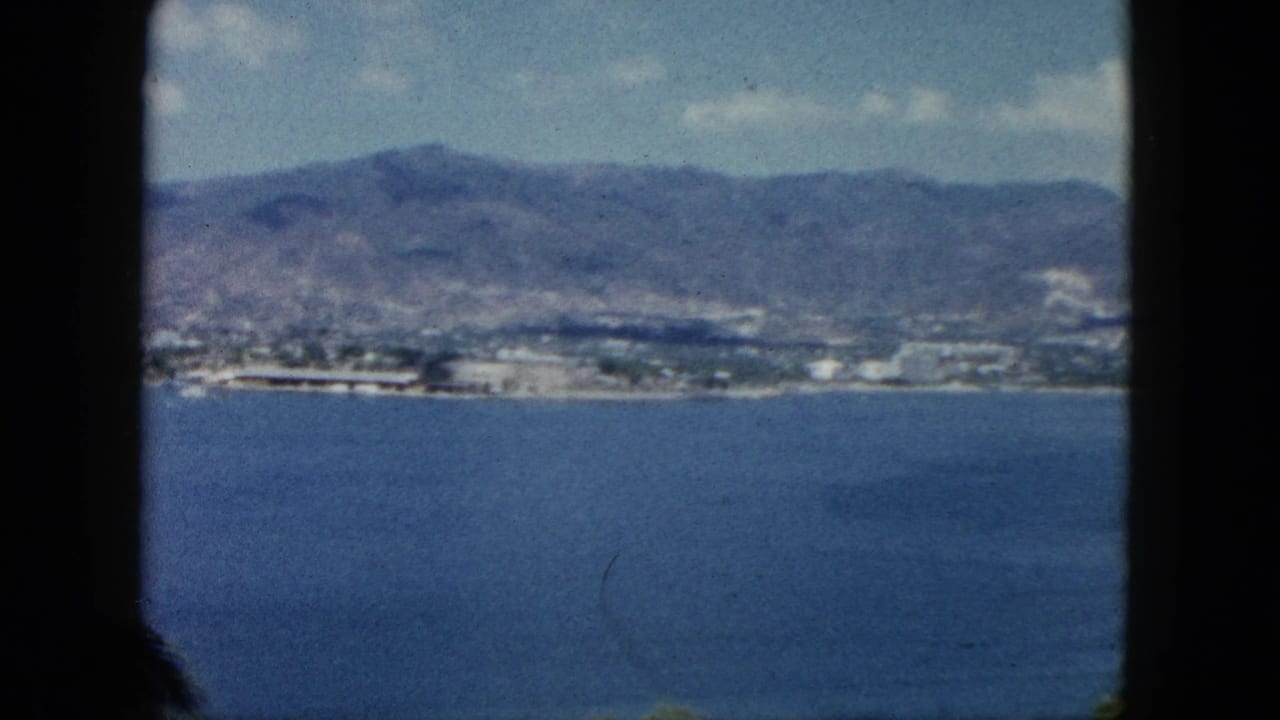 Distant shoreline and mountains across blue water, seen within dark 8mm frame borders.