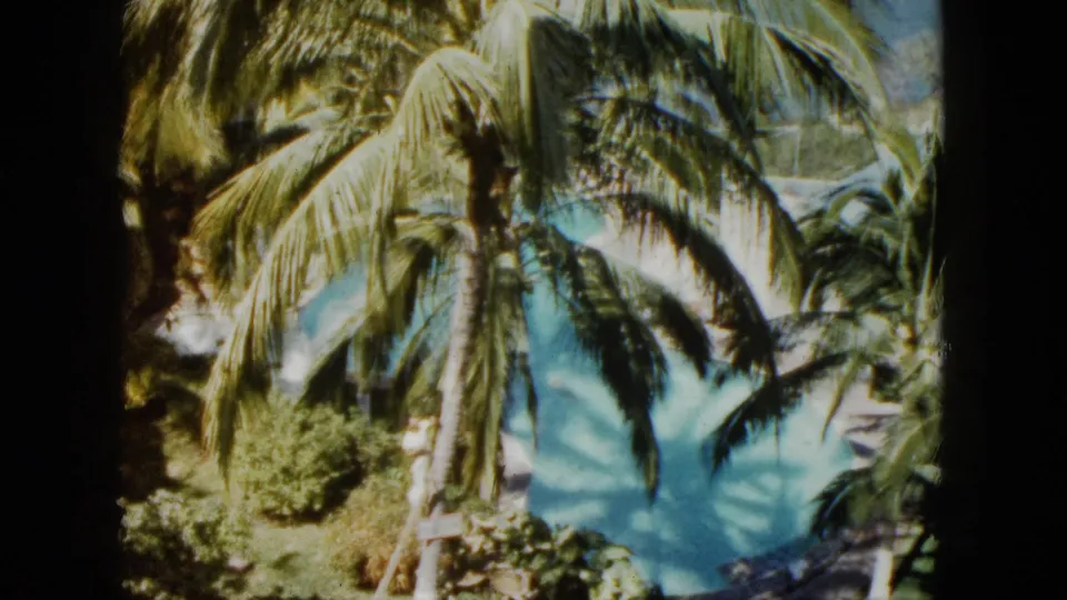Final frame of the 1962 Acapulco clip holds on palms, shrubs, and the turquoise swimming pool from above.