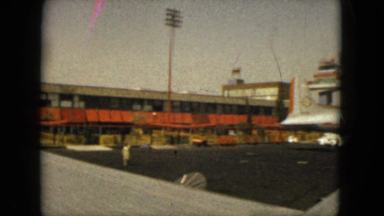 Airport terminal and tarmac with a white jet nose entering at right.