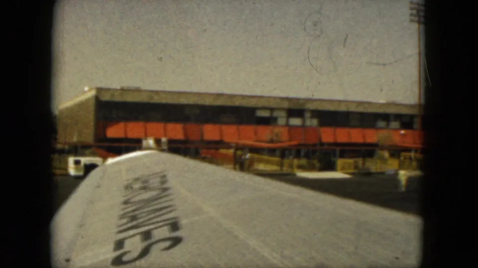 1962 Acapulco airport footage shows the aircraft wing filling the lower frame with the terminal facade and tarmac area beyond.