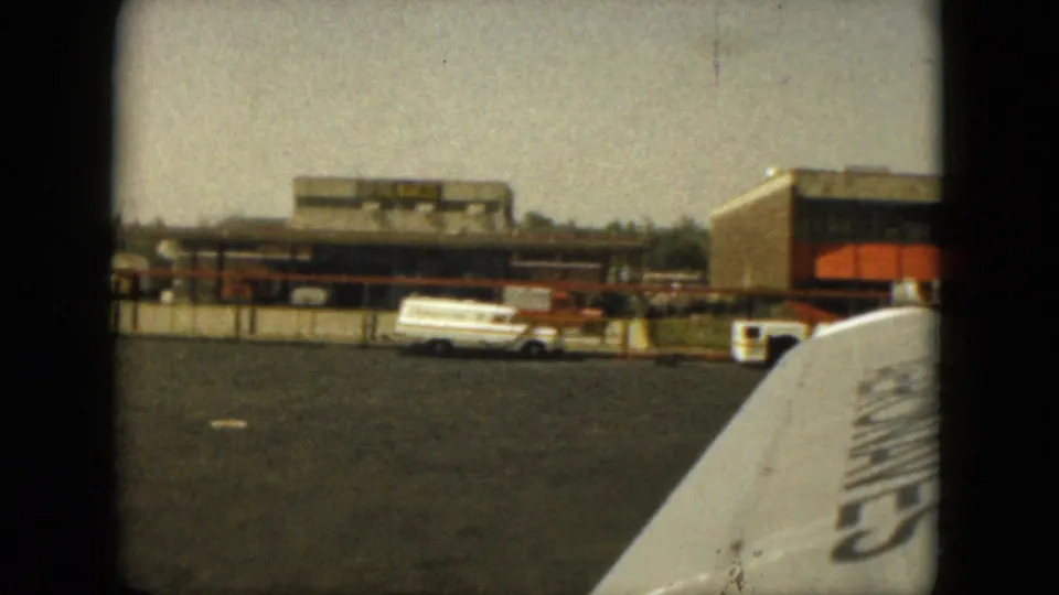 1962 Acapulco airport view showing a terminal building, service vehicle, tarmac, and part of a nearby aircraft.